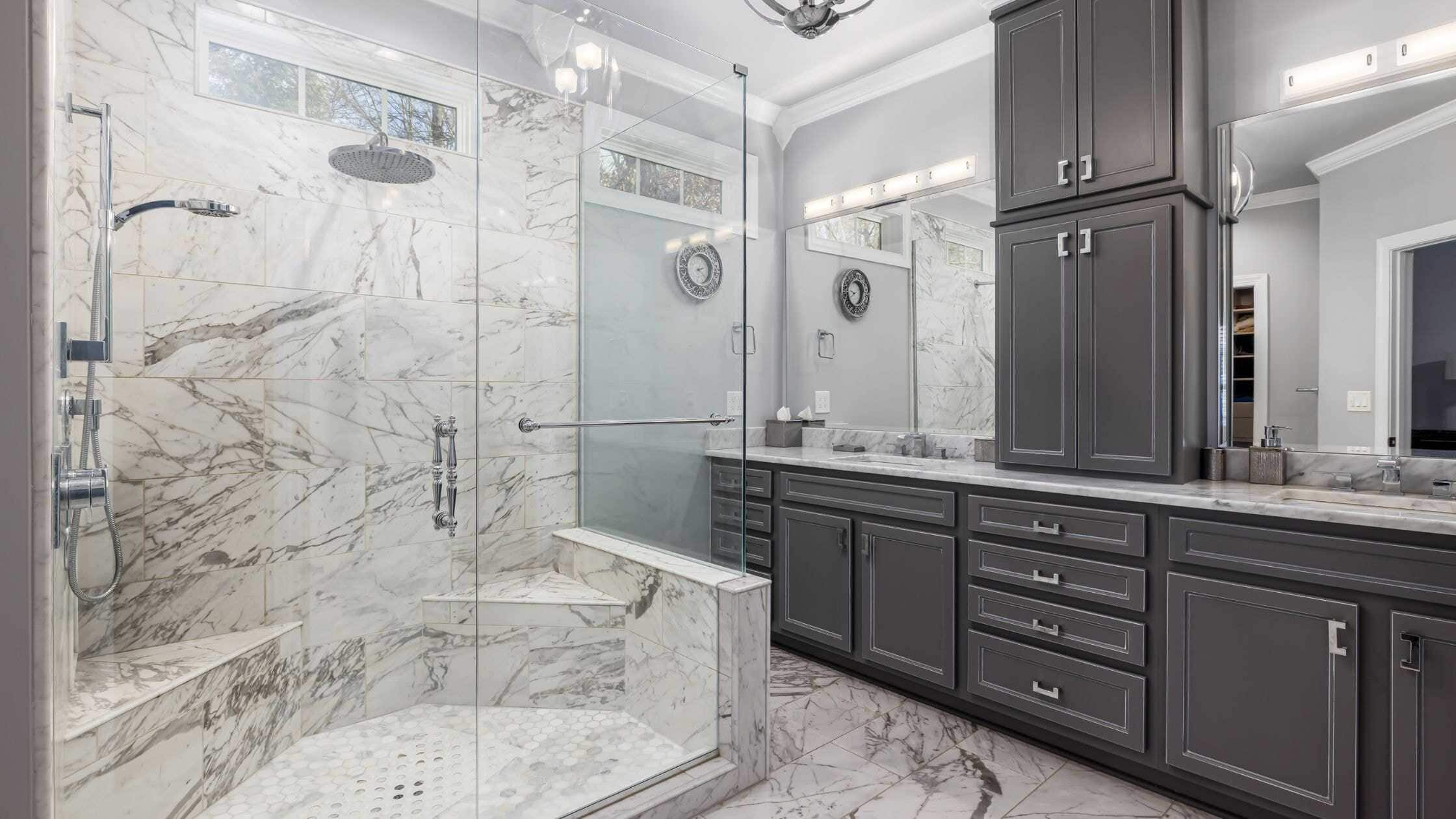 Elegant bathroom with marble tiles and a glass shower enclosure.